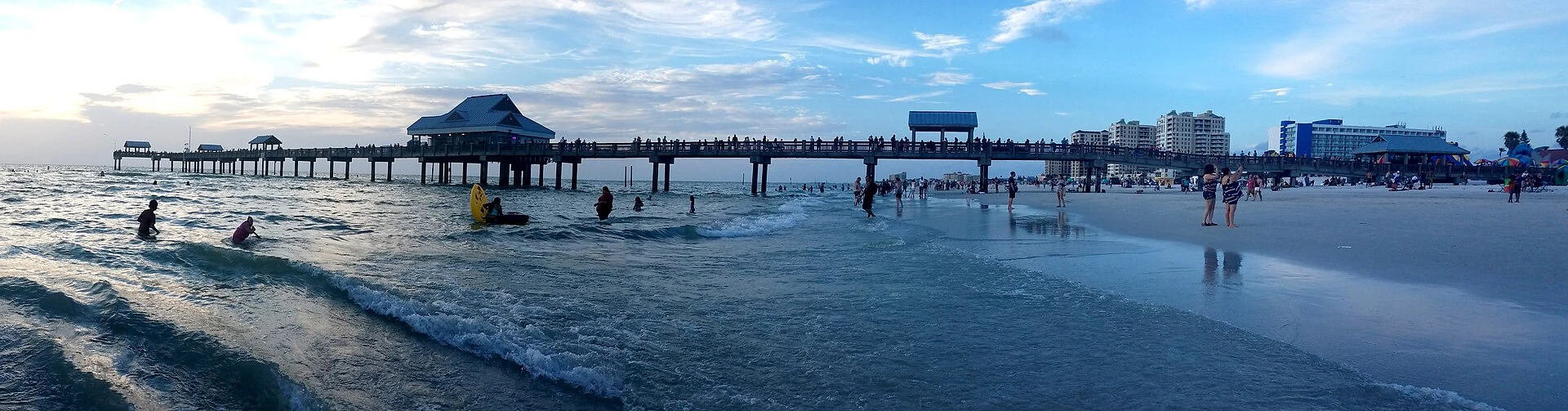 Beachgoers beside Pier 60 in a wide shoreline panorama